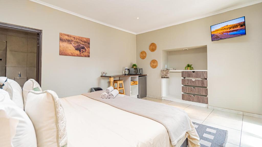 a bedroom with a large white bed and a kitchen at Bosveld In Die Stad 2 Guesthouse in Alberton