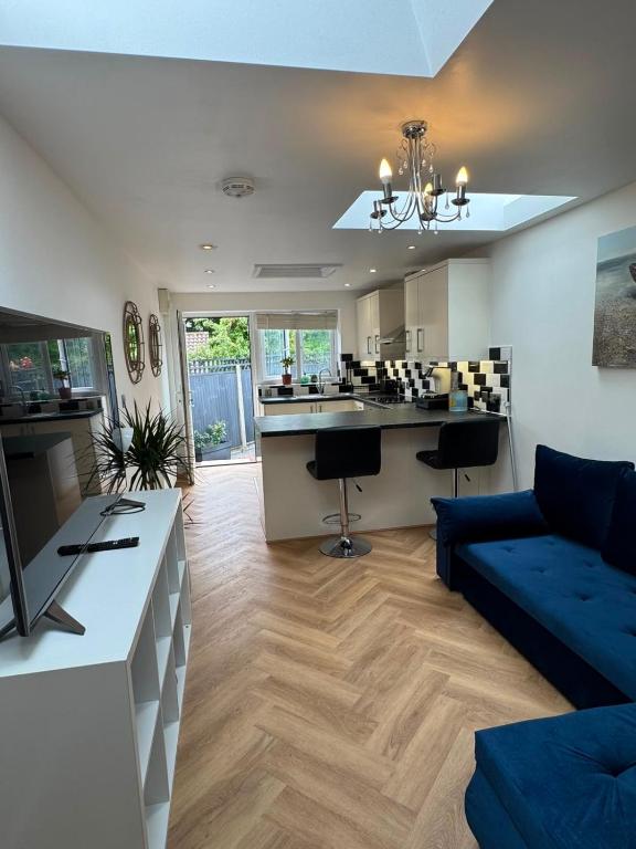 a living room with a blue couch and a kitchen at Modern peaceful property Breakfast included in Blean