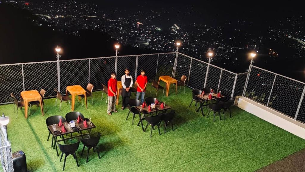 a group of people standing on a balcony at night at Naman Eco Resort in Solan