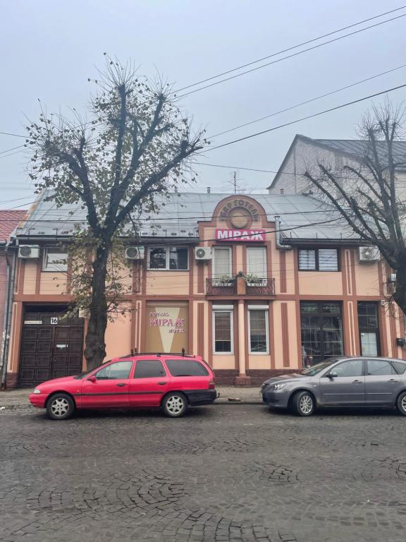 two cars parked in a parking lot in front of a building at Міраж in Uzhhorod