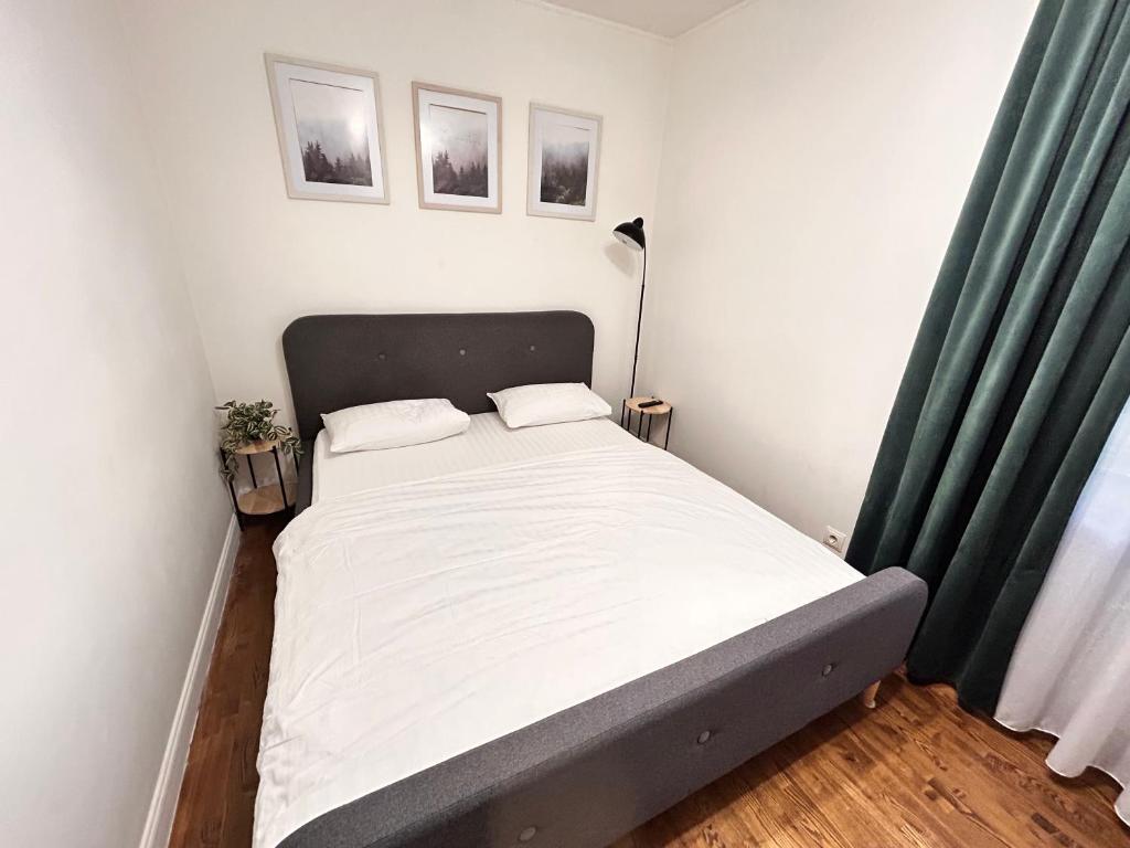 a small bedroom with a bed with green curtains at Kosenko apartments in Zhytomyr