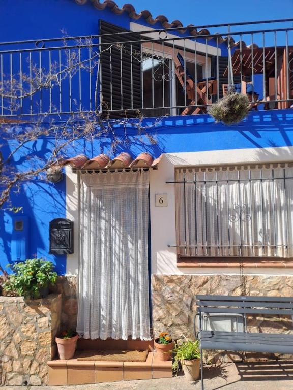 a blue building with a gate and a bench at Ca la Pepa in Begur
