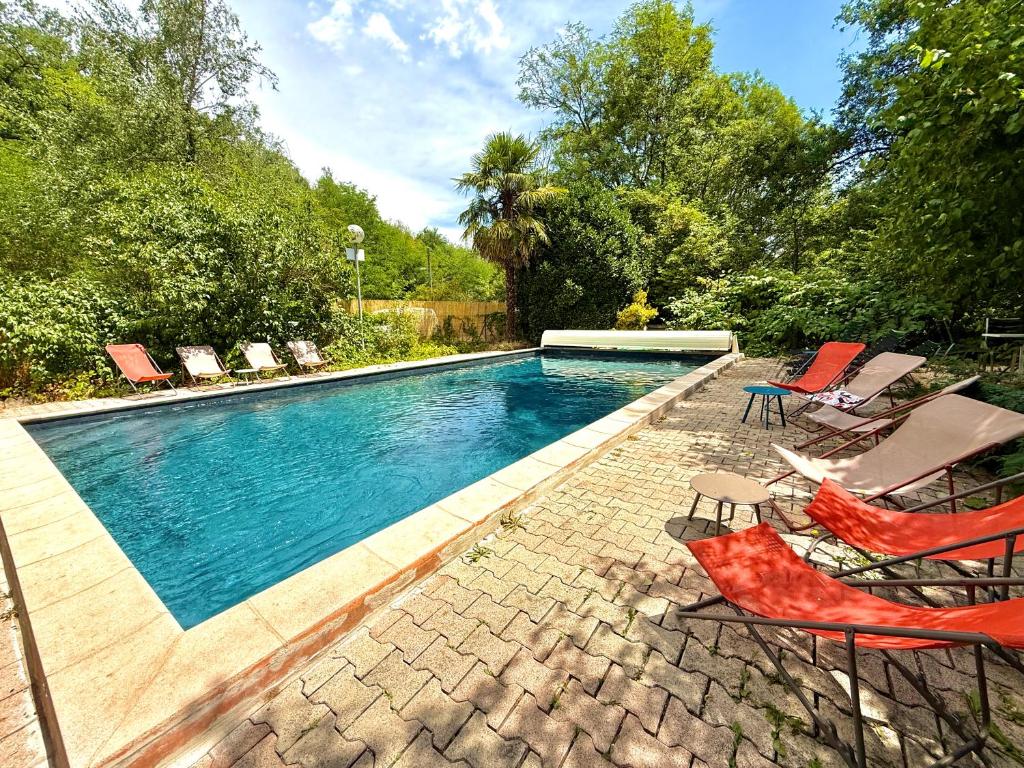 a swimming pool with two chairs and a group ofhaps at Kârma Hôtel in Saint-Genis-les-Ollières