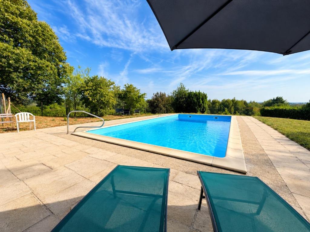 a swimming pool with two chairs and an umbrella at Le Nid du Viaur in Pampelonne