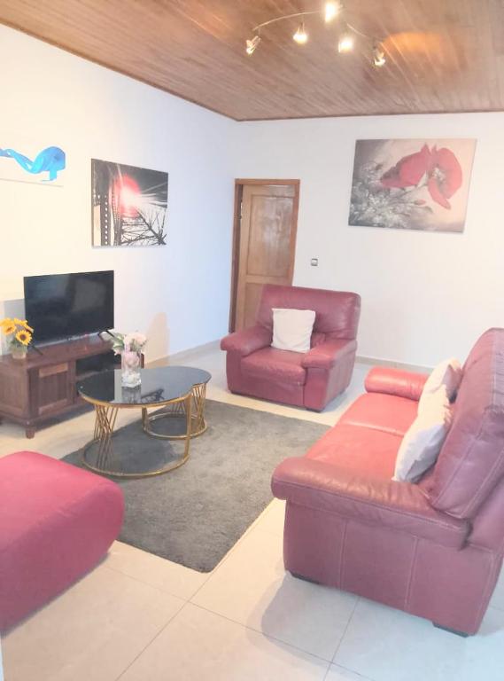 a living room with two red couches and a table at Résidence Merveilles P14 in Kribi