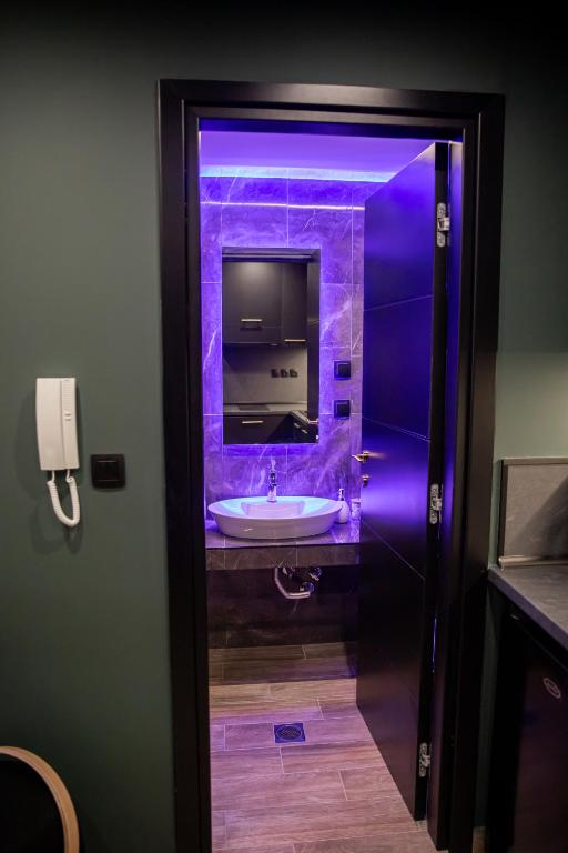 a bathroom with a sink and a purple light at Skyline suite studio in Larisa