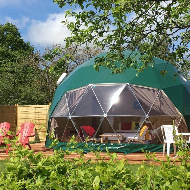 a green tent with chairs and tables in a yard at Le Nid du Tui - A proximité du Zoo de Beauval in Faverolles