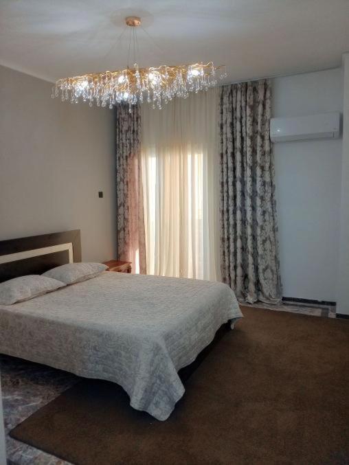 a bedroom with a large bed and a chandelier at Hera's apartment in Porto Rafti
