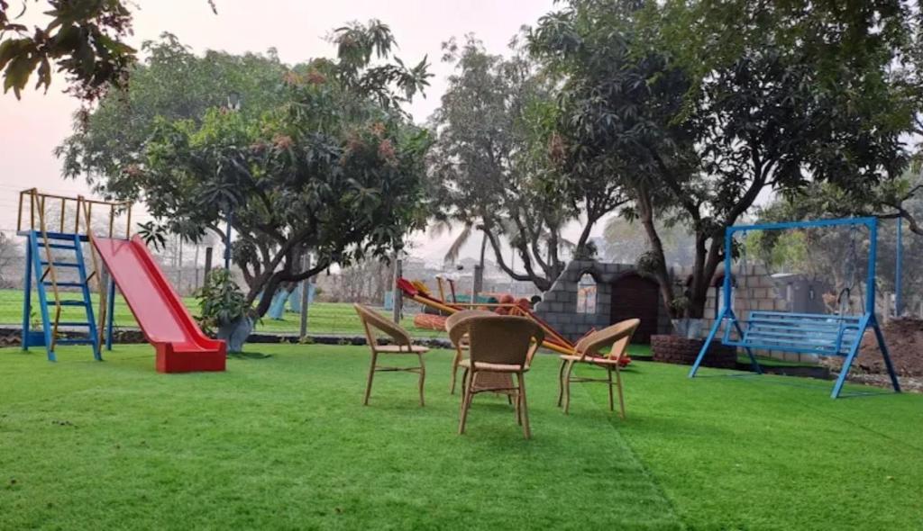 a playground with three chairs and a slide at Krishna Garden and Resort in Betgaon