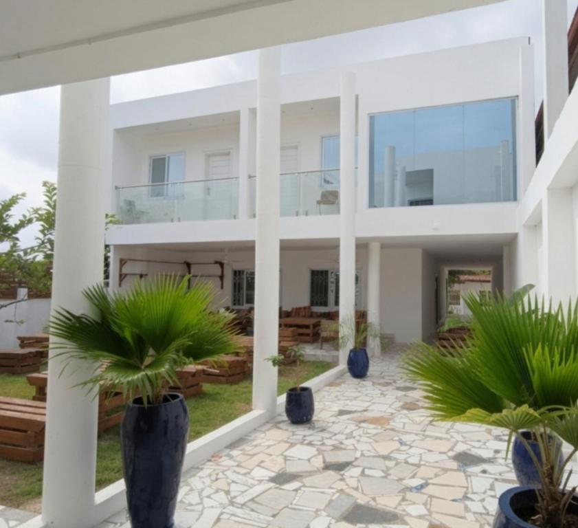 a large white house with two potted plants at The Hills in Accra