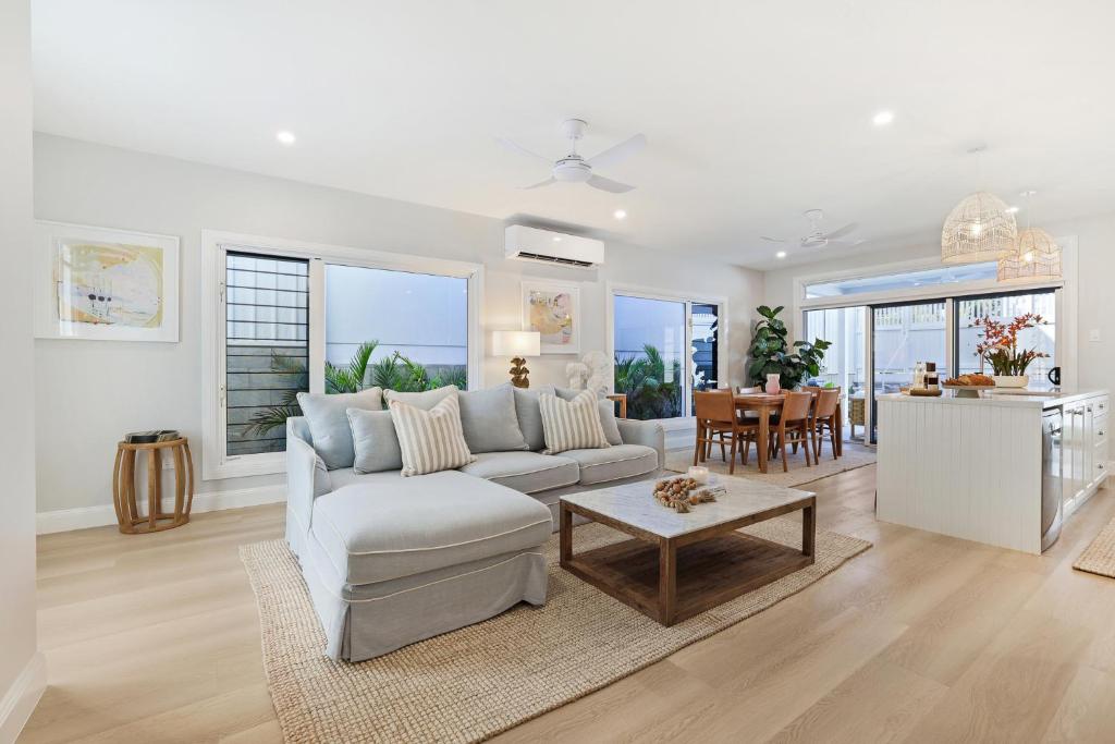 a living room with a white couch and a table at Basalt Beach House in Bargara