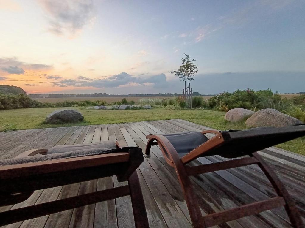a rocking chair on a wooden deck with a view of a field at Ostseeseele in Parin