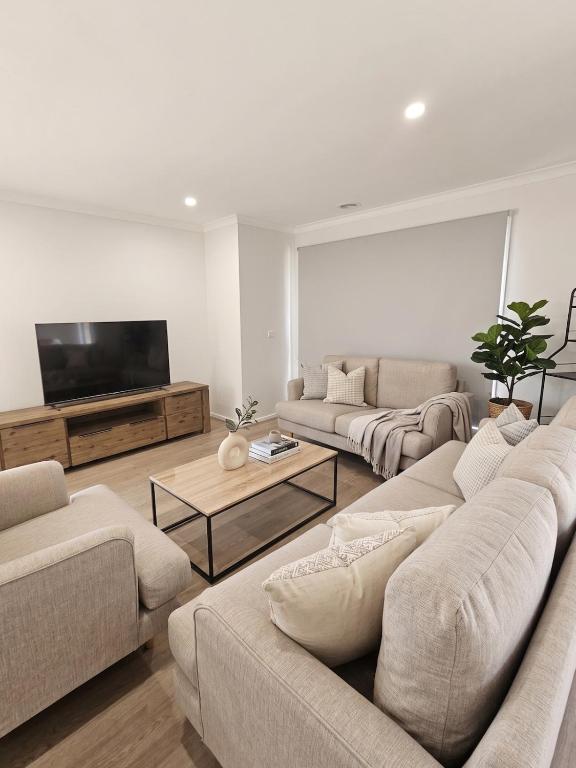 a living room with couches and a flat screen tv at St Germain House, Clyde North in Clyde North