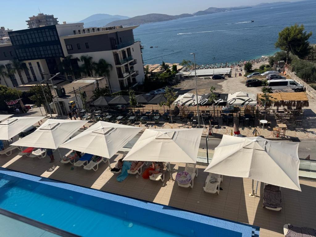 a view of a pool with umbrellas and a beach at Dania Sea View Apartments in Sarandë