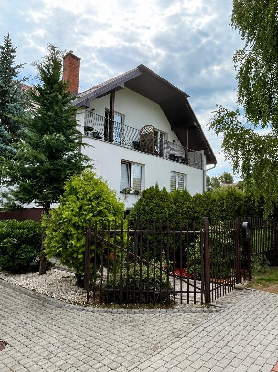 a white house with a fence in front of it at Pokoje na Brzozowej 2 in Białogóra
