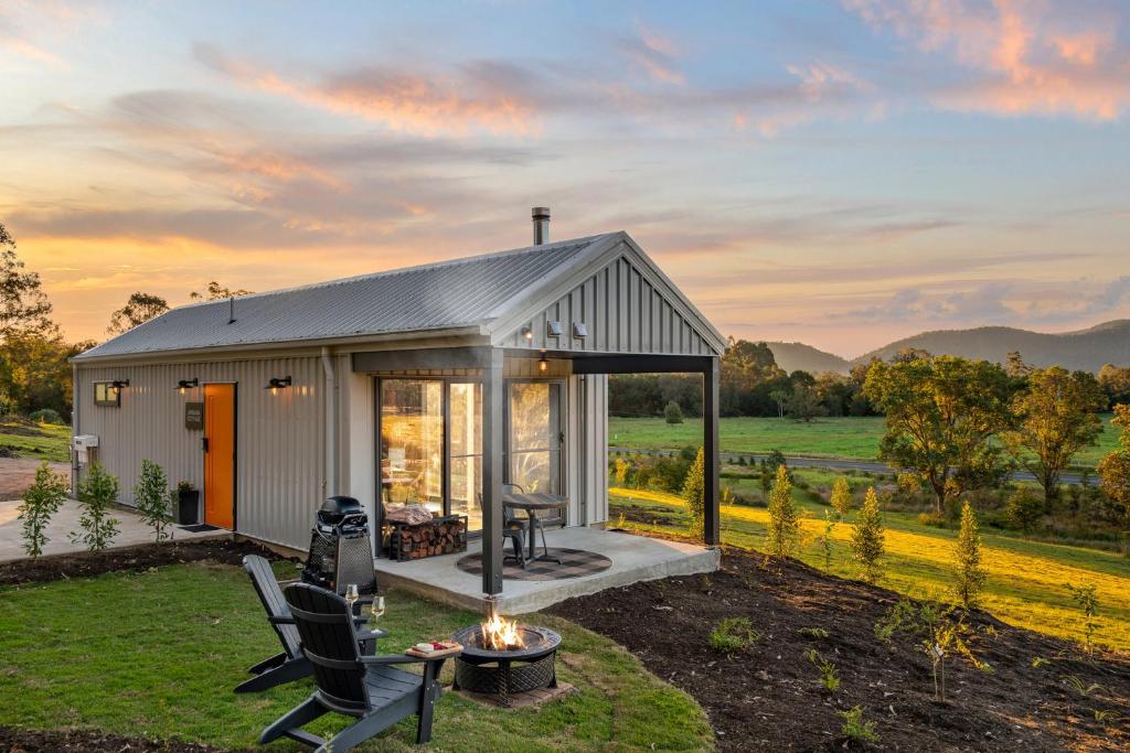 a small white shed with a fireplace in a yard at Jinibara Cottage in Conondale