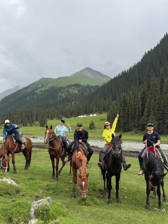 a group of people riding horses in a field at Asiya in Karakol
