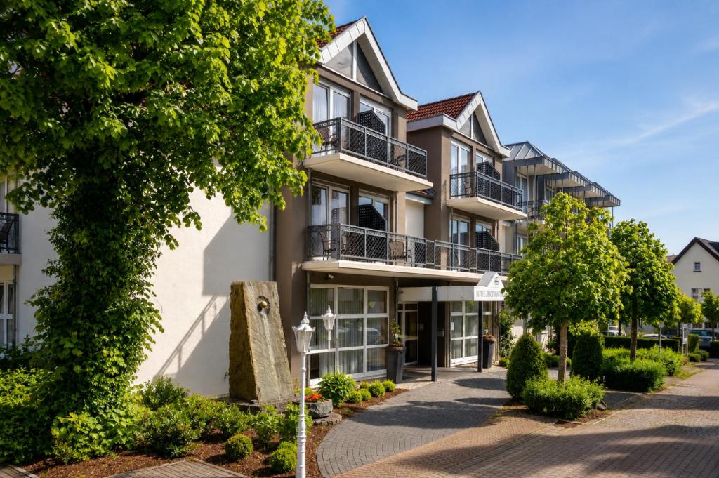 an apartment building with balconies and trees at Kurhotel Grüttner mit eigenem Sole Thermal Schwimmbad 32 Grad und Saunalandschaft in Erwitte
