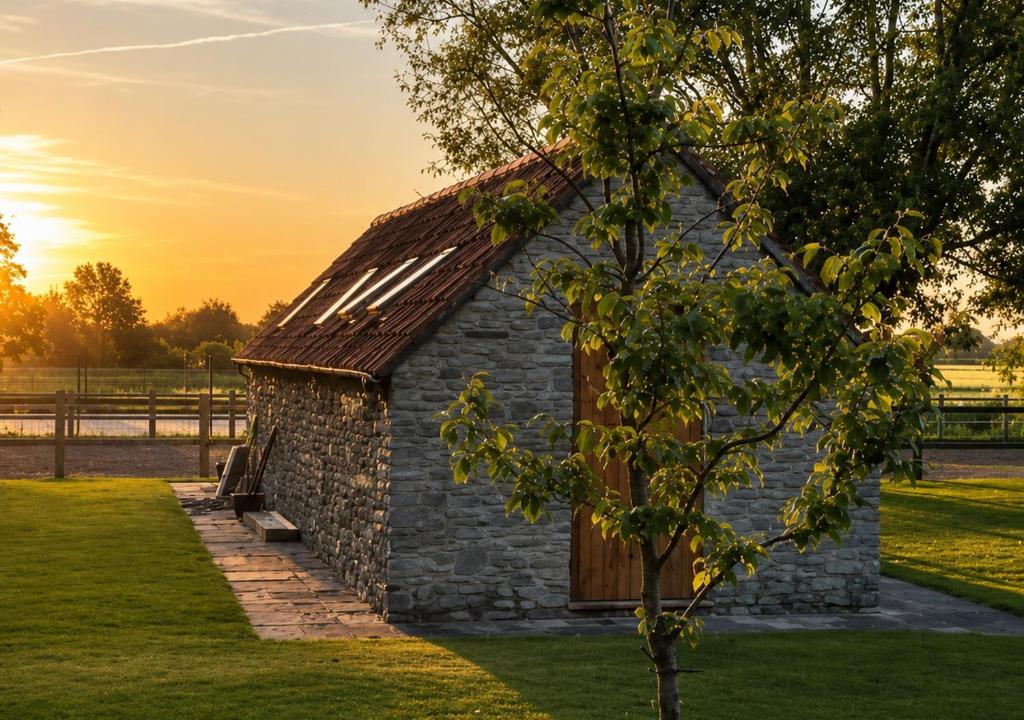 an old stone barn in a field with a tree at Plgs and Blankets in Pucklechurch
