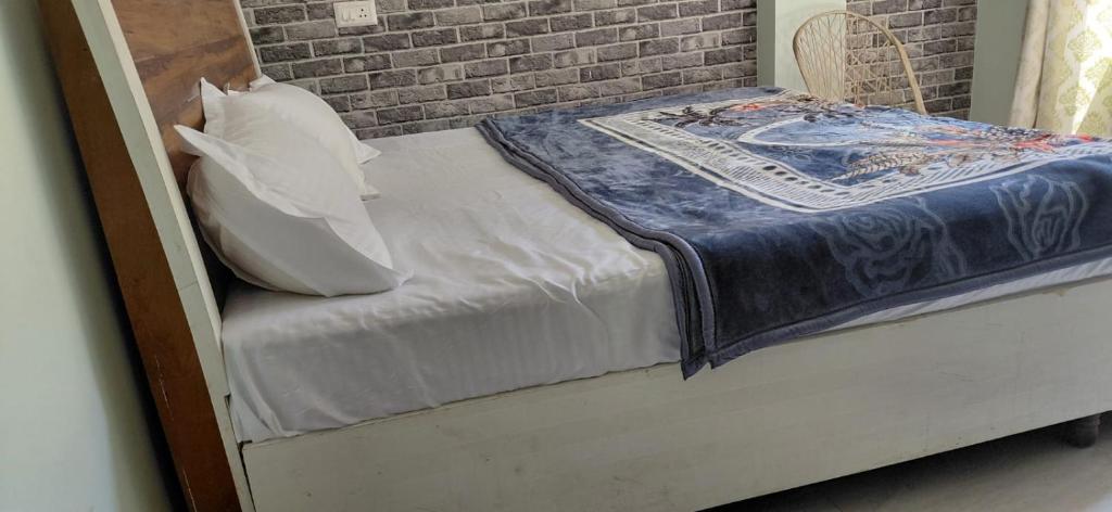 a small bed in a room with a brick wall at Kaushalya River View in Solan