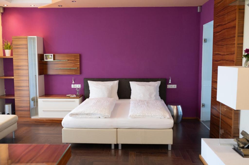 a bedroom with a purple wall and a bed at HOTEL MARIA in Gramatneusiedl