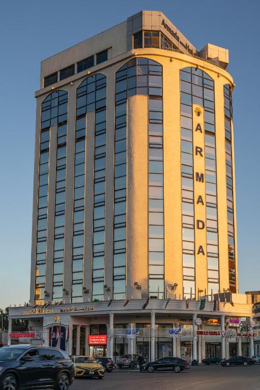 a large building with cars parked in front of it at Armada Avenue Hotel Amman in Amman