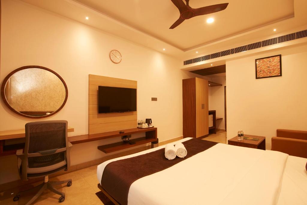 a bedroom with a bed and a desk and a television at Clickon Value Seven Hills in Chik Bānavar