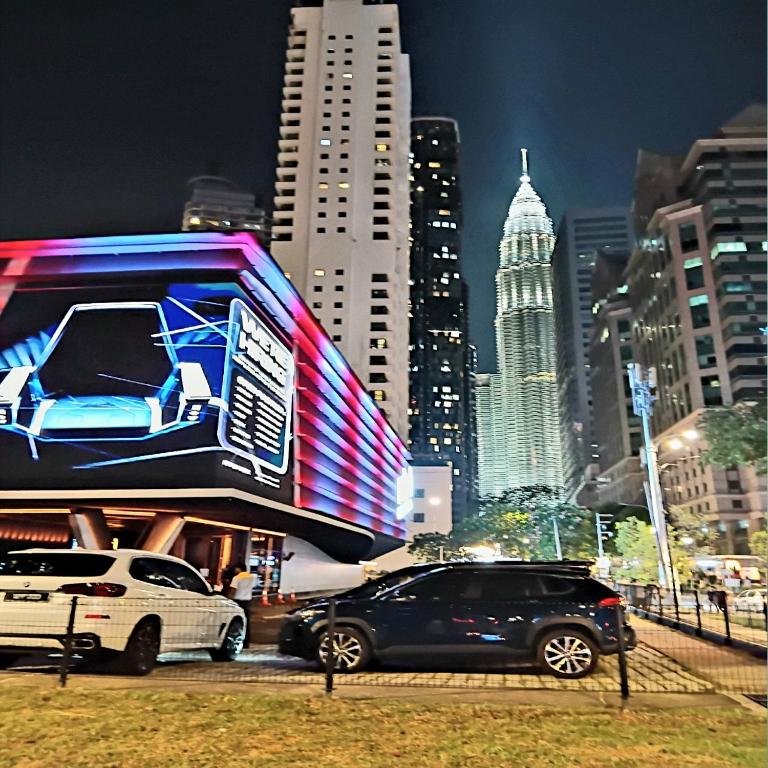 two cars parked in front of a billboard in a city at Vortex suites klcc by kl cozy home in Kuala Lumpur