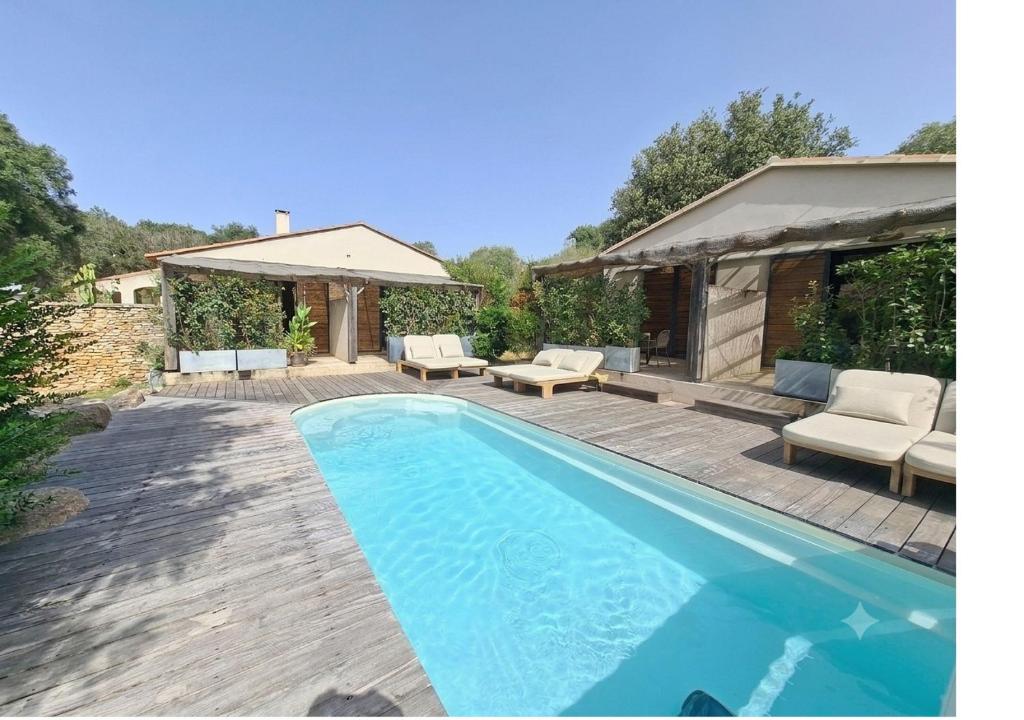 a swimming pool with a deck and a house at Songes d’été in Bonifacio