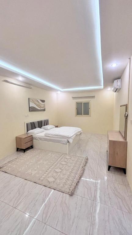a white bedroom with a bed and a table at شقق مفروشة الباحة in Al Baha