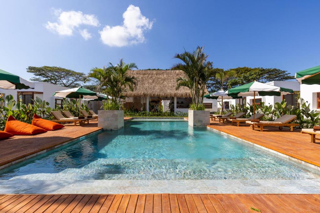 a pool at a resort with chairs and umbrellas at Alcazaba Resort Lombok in Kuta Lombok