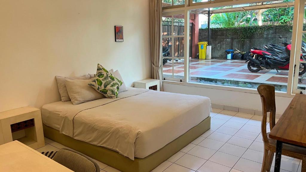 a bedroom with a bed and a motorcycle outside a window at Casavina residen kubu manyar 201 in Canggu
