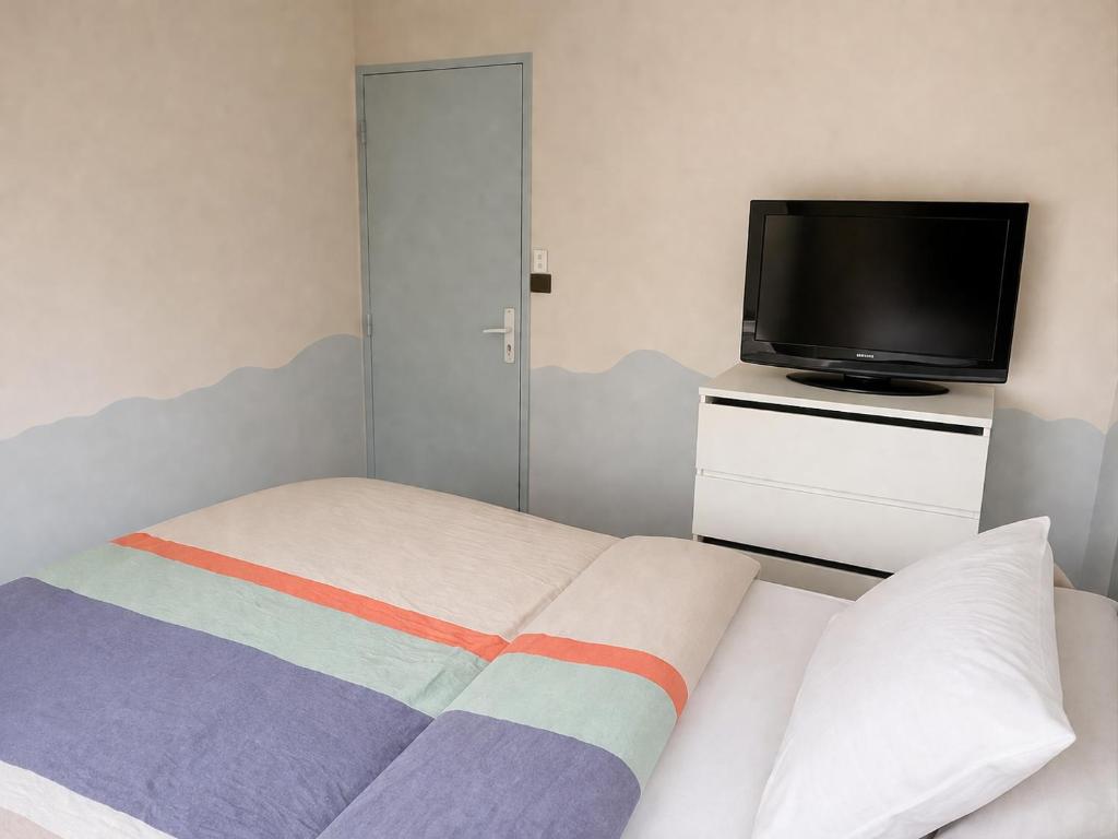 a bedroom with a bed and a flat screen tv at Prestige appart in Chalon-sur-Saône