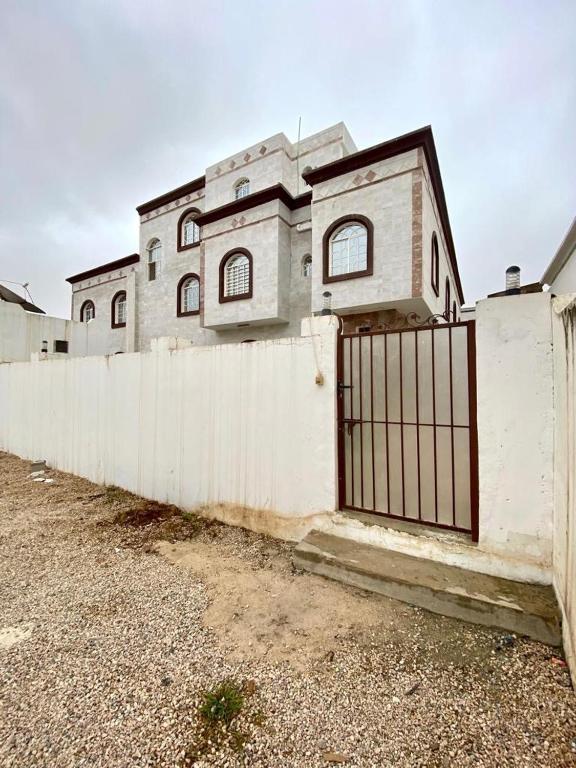 a white fence with a gate in front of a house at فيلا in Salalah