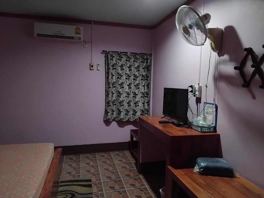 a bedroom with a bed and a desk with a fan at Saran Resort room 5 in Ban Khok Wat