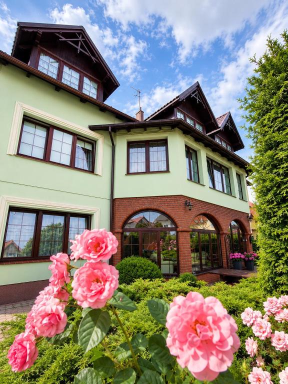 a house with pink flowers in front of it at Magnat Dźwirzyno in Dźwirzyno