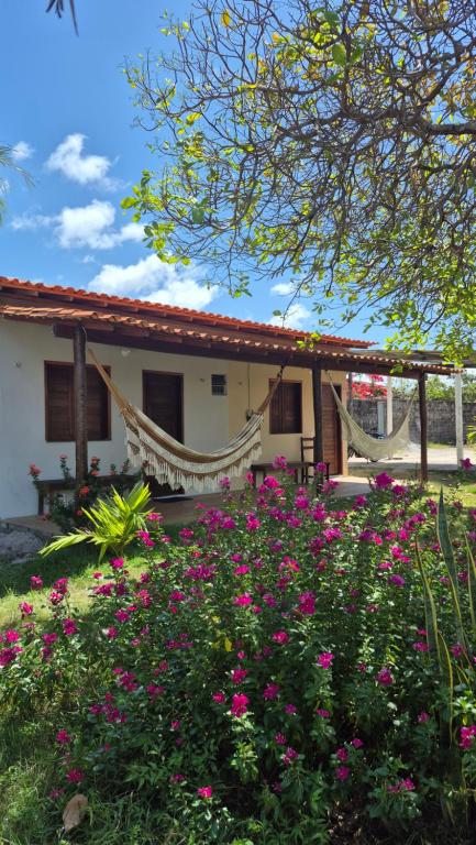 a house with hammocks and flowers in front of it at Chalé Renilton Turismo in Santo Amaro