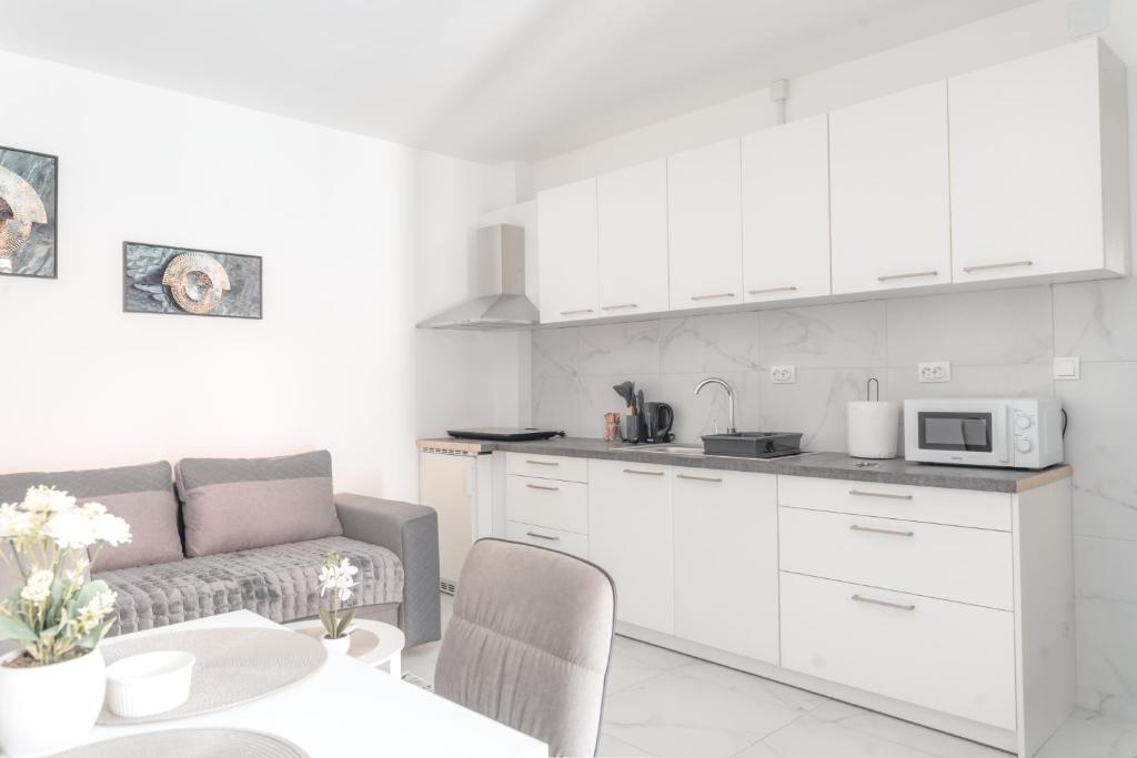 a white kitchen with a couch and a table at Nora Apartments in Jagodina