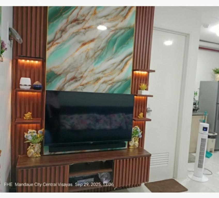 a flat screen tv on a stand with a painting at Lloyds Barato 2BR Condo Unit 6paxMax in Mandaue City