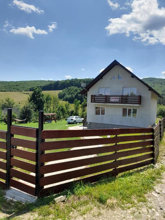 a house behind a fence in front of a field at Casă Bubu in Cacica