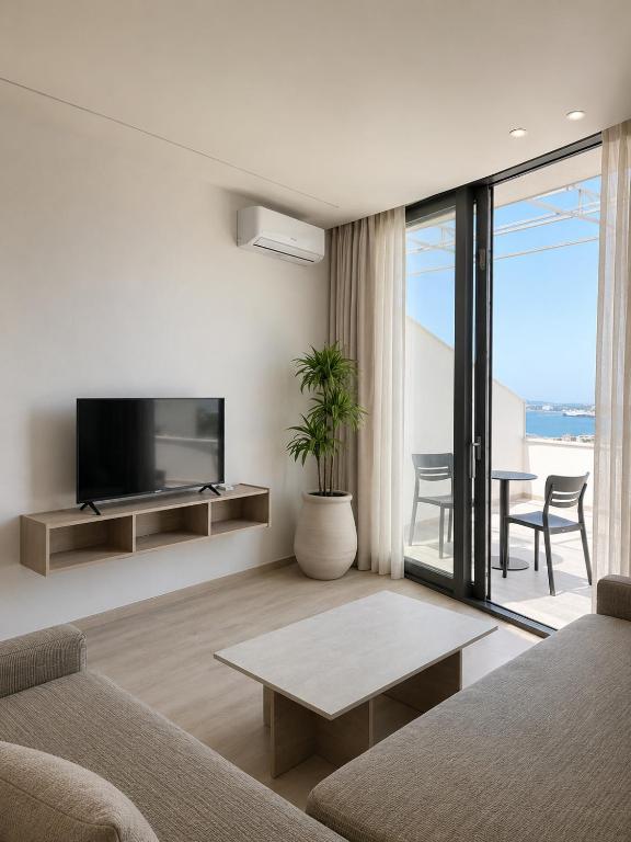 a living room with a couch and a tv and a table at Emera Apartments in Vlorë