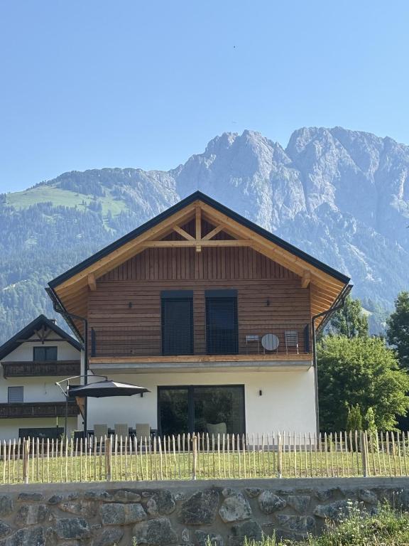 a house with a fence and mountains in the background at Sportchalet Bergkristall regio Nassfeld Presseggersee in Kirchbach
