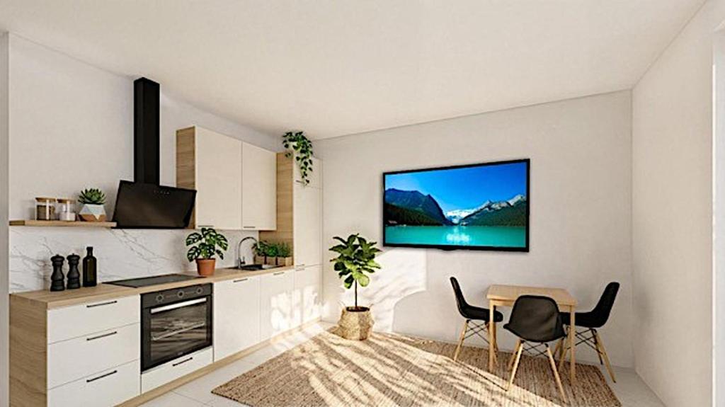 a kitchen with a table and a tv on a wall at Apartment am Moosrain in Eitting