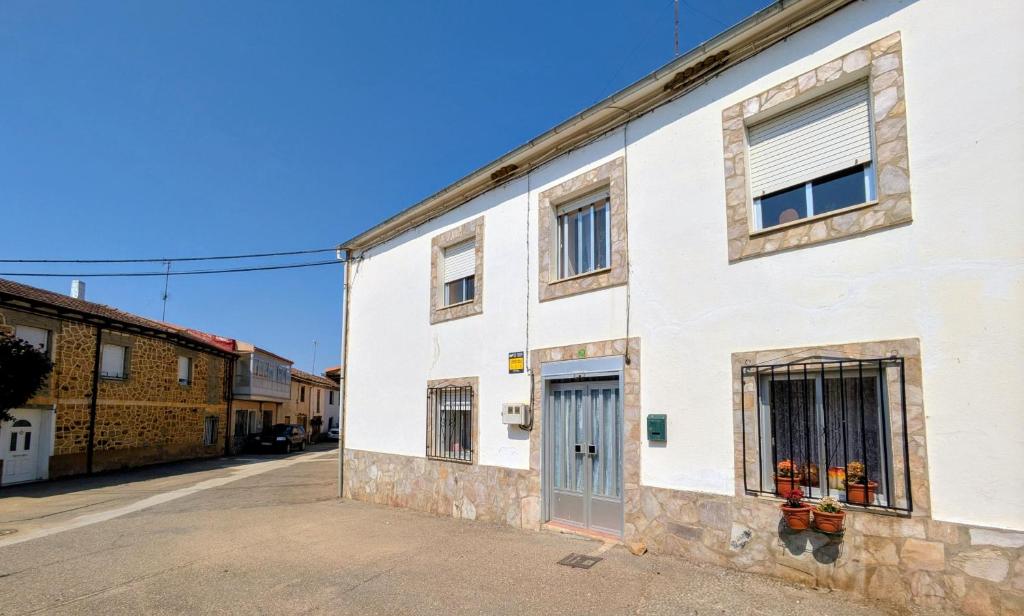 a white building with a door on a street at Casa Ti Mielga in Ayoó de Vidriales
