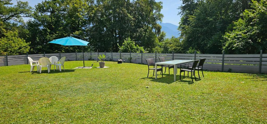 a table and chairs with an umbrella in a yard at Chambre Zen Et Calme in Bouveret