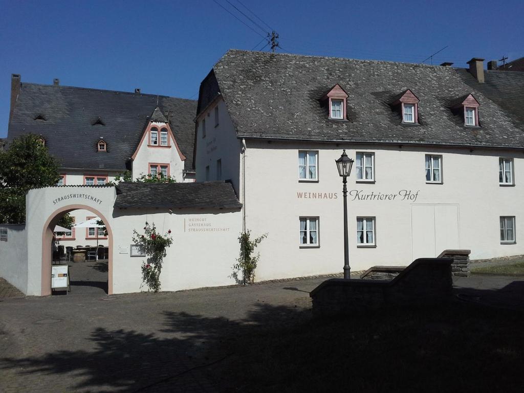 ein weißes Gebäude mit einem Bogen davor in der Unterkunft Weinhaus Kurtrierer Hof in Leiwen