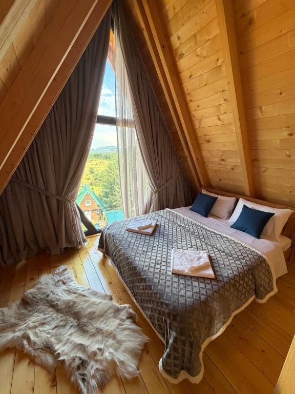 a bed in a room with a large window at Durmitor Den in Žabljak