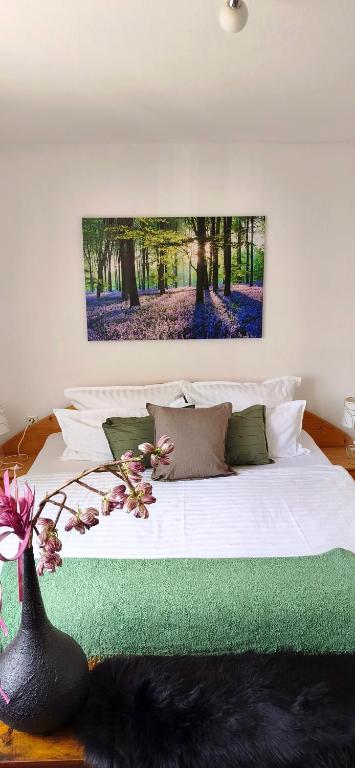 a bedroom with a white bed with a painting on the wall at FeWo Sartorius am Hemsberg in Bensheim