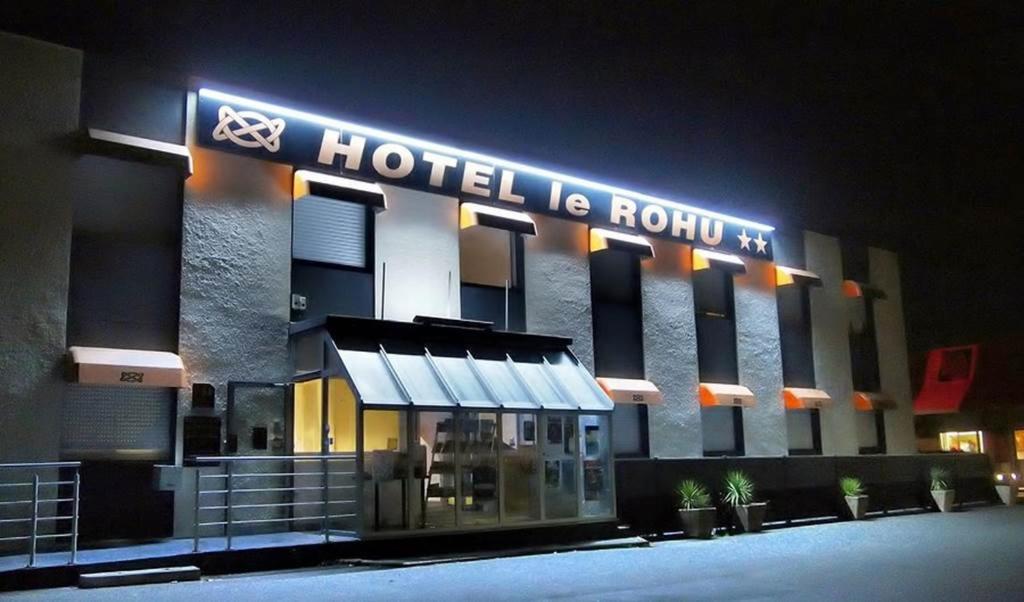a hotel building with a sign on it at night at Hotel Le Rohu Vannes in Séné