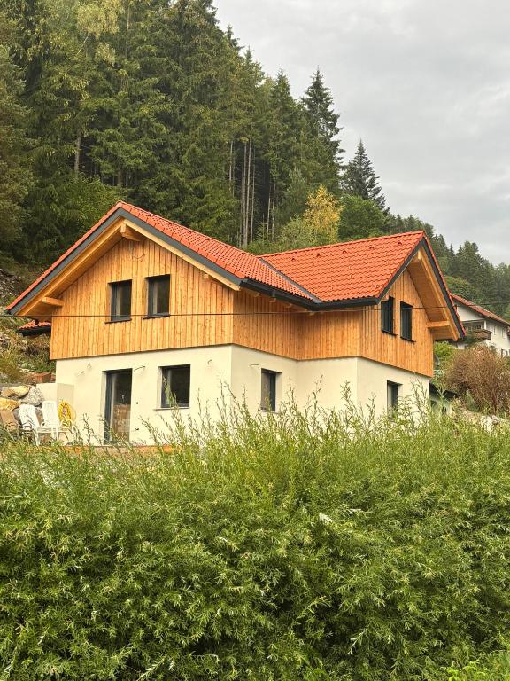 a house with a wooden roof on top of a field at SchiScho's Lodge in Sankt Kathrein am Offenegg